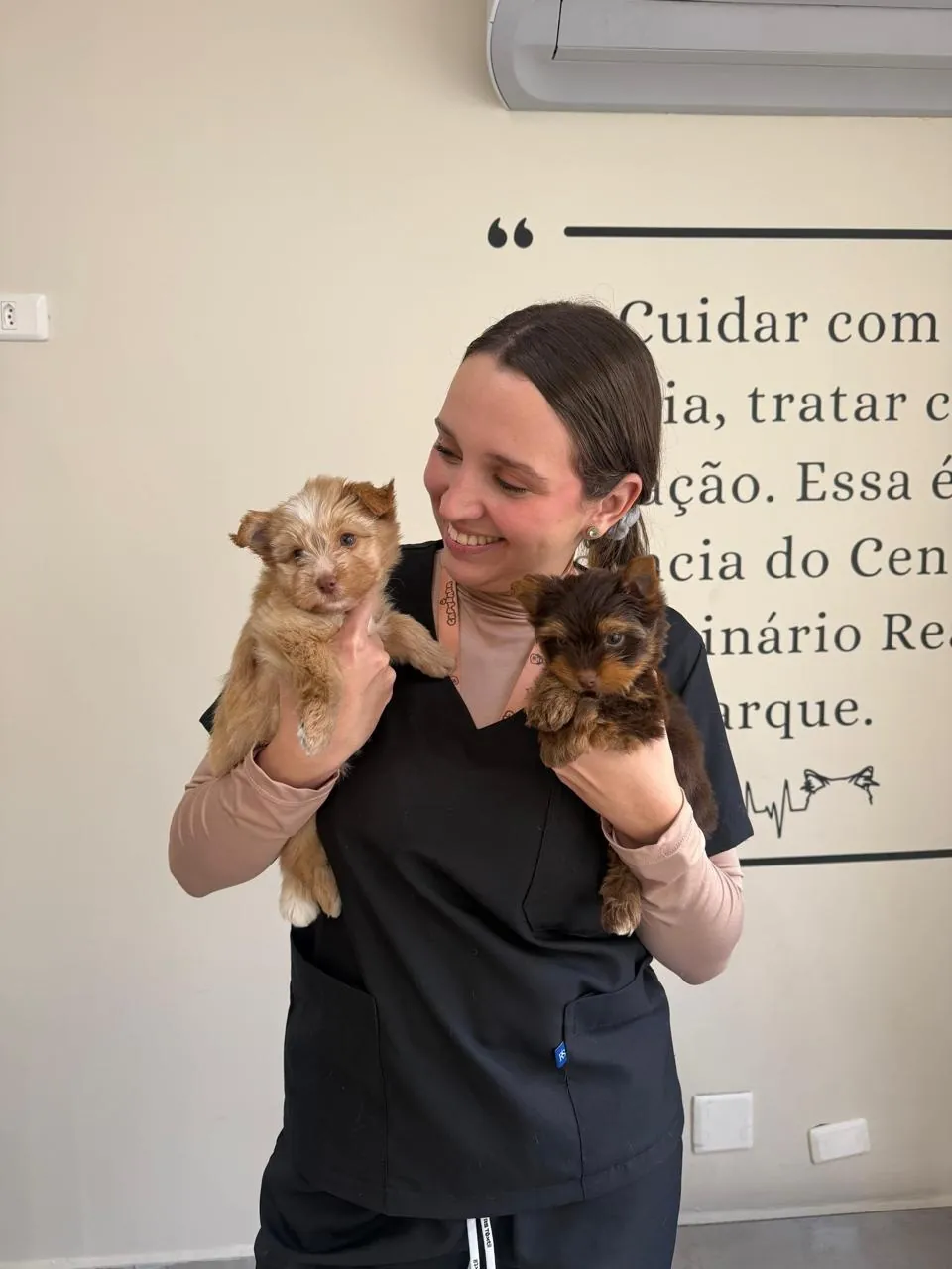 Veterinária sorrindo com dois cachorrinhos no colo