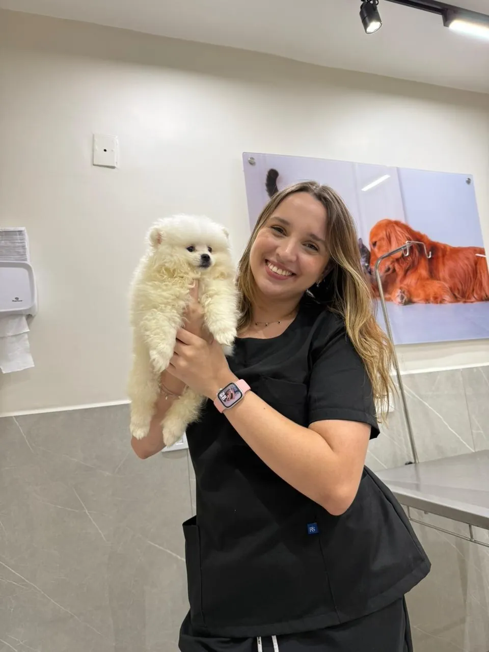 Veterinária do Real Parque sorrindo com um lulu-da-pomerânia branco no colo